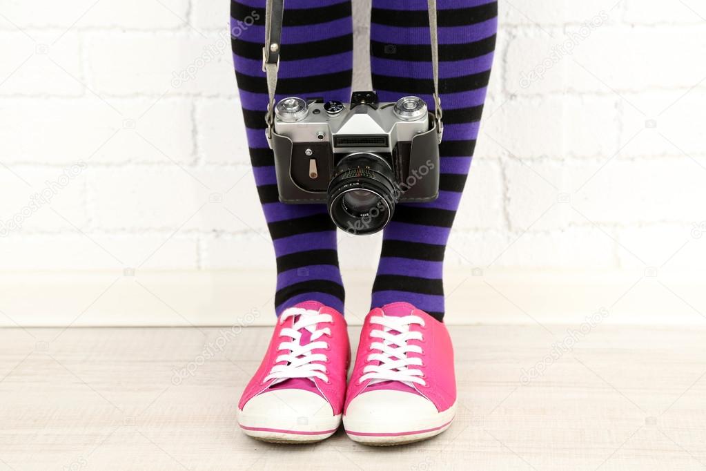 Girl in sneakers with retro camera