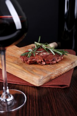 Bir bardak şarap ile ahşap arka plan üzerinde ızgara biftek