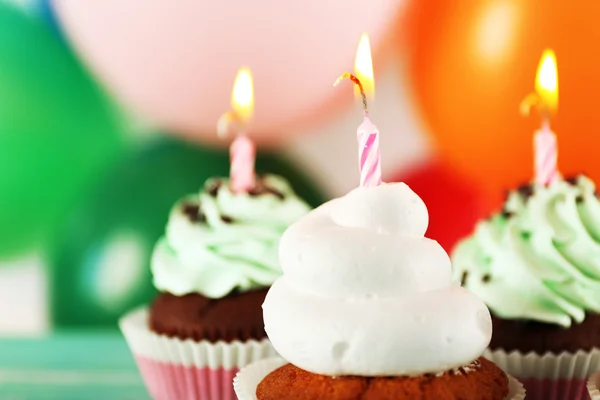 Deliciosos cupcakes de aniversário na mesa em fundo brilhante — Fotografia de Stock