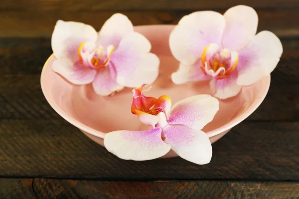 Cuenco con orquídeas sobre fondo de madera —  Fotos de Stock