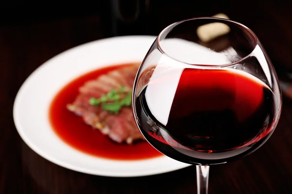 Copa de vino con filete a la parrilla en salsa de vino sobre fondo oscuro — Foto de Stock