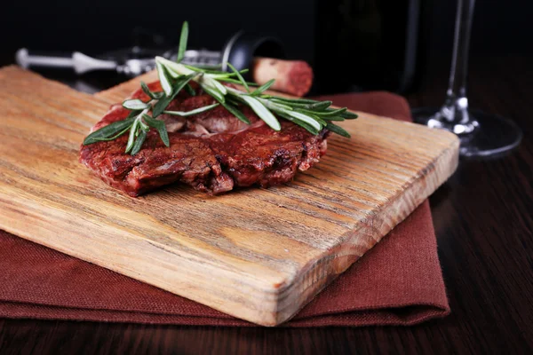 Gegrilde steak met fles wijn op donkere achtergrond — Stockfoto