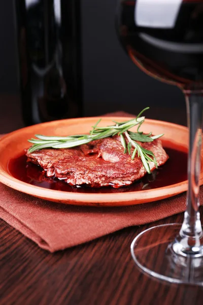 Glass of wine with grilled steak in wine sauce on dark background — Stock Photo, Image