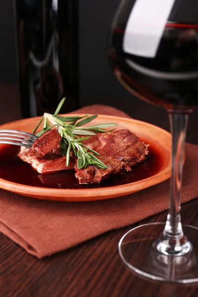 Glass of wine with grilled steak in wine sauce on dark background — Stock Photo, Image