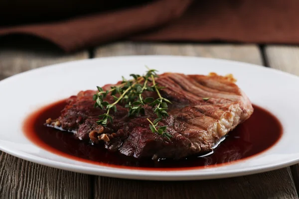 Bife grelhado em molho de vinho no prato na mesa de perto — Fotografia de Stock