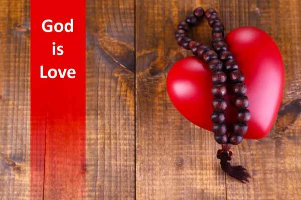 Coração com contas rosário em fundo de madeira e texto Deus é Amor — Fotografia de Stock
