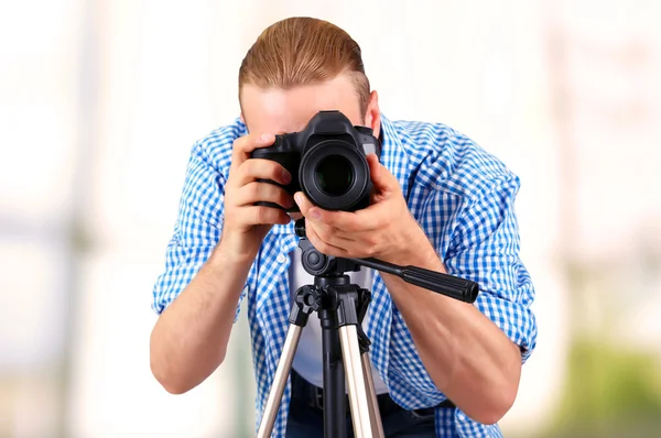 Schöner Fotograf mit Kamera auf Stativ drinnen — Stockfoto