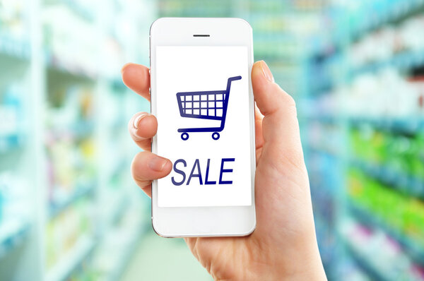 Mobil alışveriş kavramı. Süpermarket arka plan üzerinde internet alışveriş için cep telefonu tutan el — Stok fotoğraf
