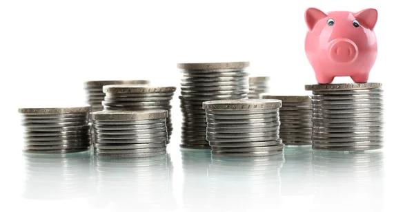 Piggy bank stojący na stosie monet na białym tle — Zdjęcie stockowe