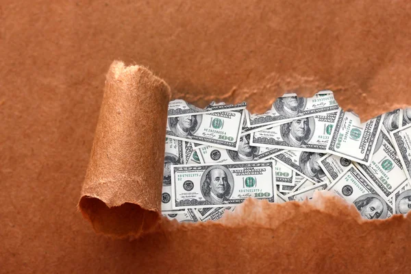 Dólares a través de papel artesanal roto —  Fotos de Stock