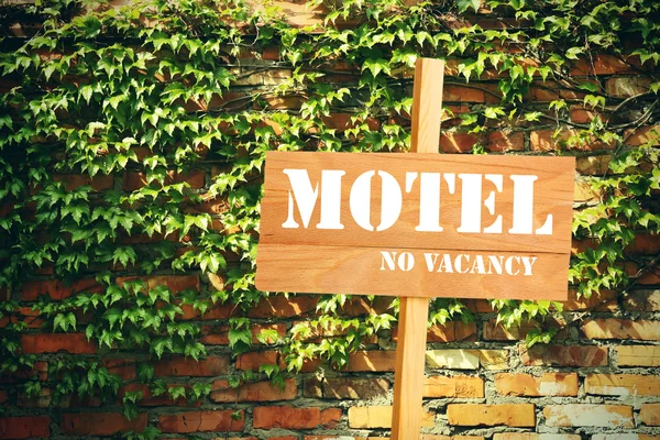 Vývěsní štít s textem Motel, No Vacancy nedaleko hotelu na cihlovou zeď pozadí — Stock fotografie