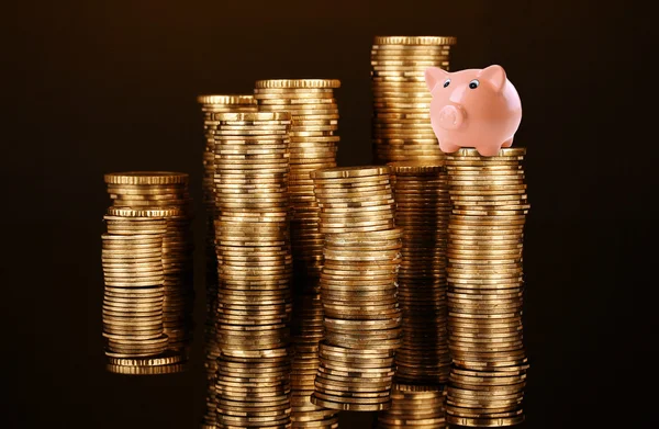 Hucha de cerdo de pie en la pila de monedas aisladas en negro —  Fotos de Stock