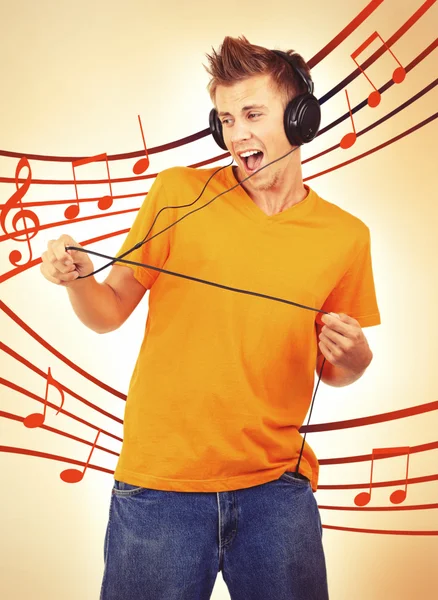 Young man with headphones listening music on bright background — Stock Photo, Image