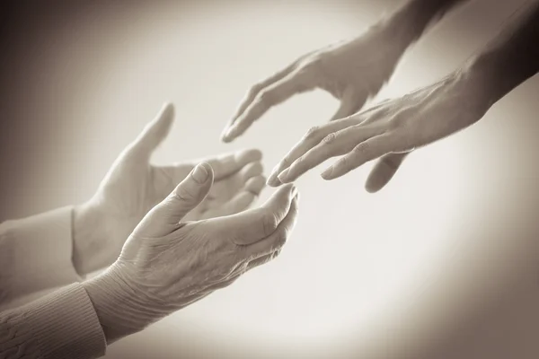 Old and young holding hands on light background, closeup — Stok Foto