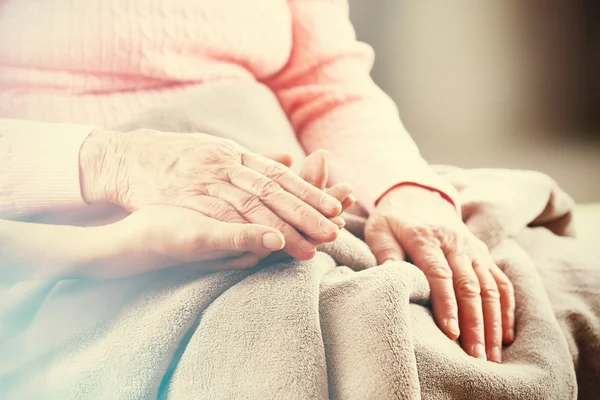 Gamla och unga hand i hand på ljus bakgrund, närbild — Stockfoto