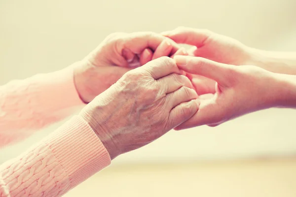 Old and young holding hands on light background, closeup — Stock Photo, Image