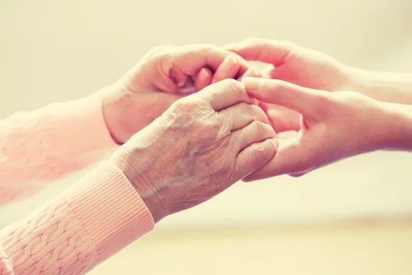 Vecchi e giovani che si tengono per mano su sfondo chiaro, primo piano — Foto Stock