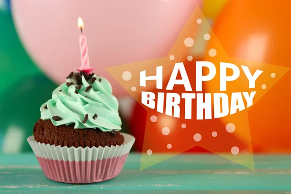 Delicioso cupcake de aniversário na mesa no fundo brilhante — Fotografia de Stock