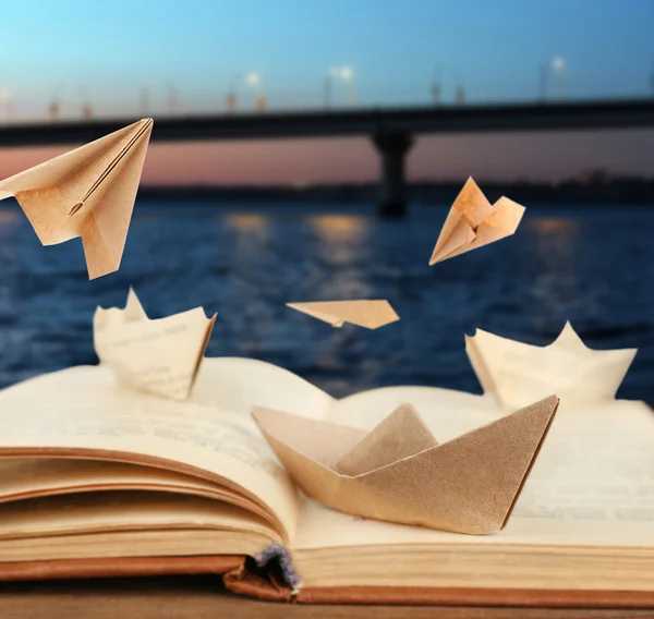Origami lodě na staré knize na pozadí bridge — Stock fotografie