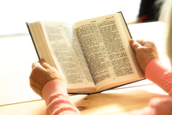 Hände einer alten Frau mit Bibel auf dem Tisch, Nahaufnahme — Stockfoto