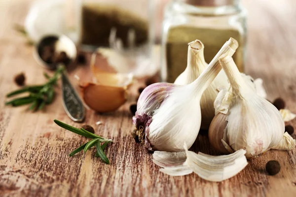 Rauwe knoflook en kruiden op houten tafel — Stockfoto