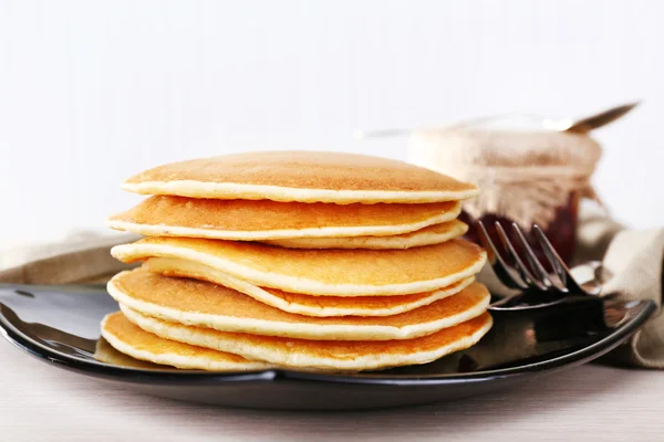 Pilha de panquecas na placa na mesa e fundo claro — Fotografia de Stock