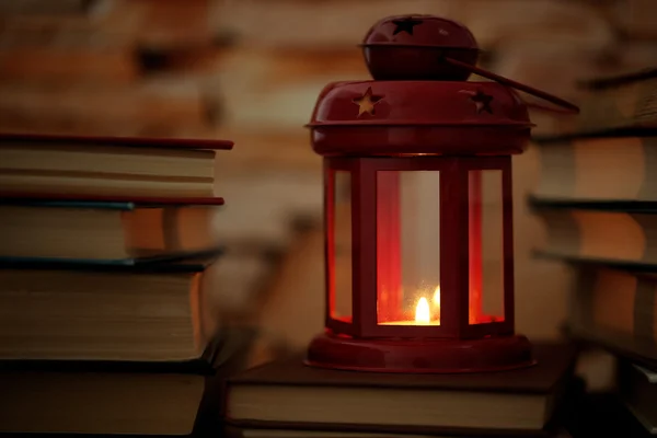 Книги и декоративный фонарь на фоне стола и кирпичной стены — стоковое фото