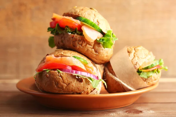 Sandwiches with salmon on plate, on wooden background — Stock Photo, Image