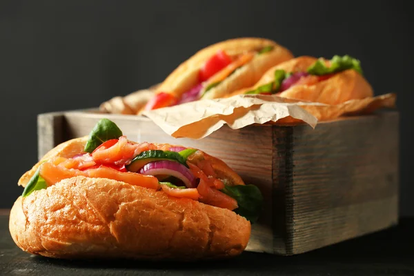 Sandwiches con salmón en caja de madera sobre fondo de madera oscura — Foto de Stock