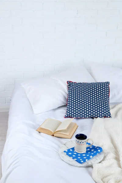 Book and cup of tea on bed close-up — Stock Photo, Image