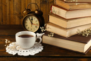 Kitap ve ahşap arka plan üzerinde saat ile çay