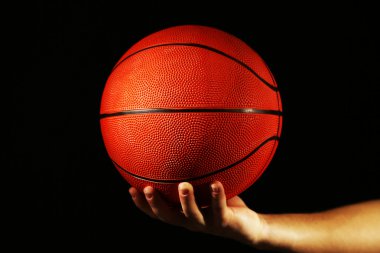 Basketball player holding ball, on dark background clipart