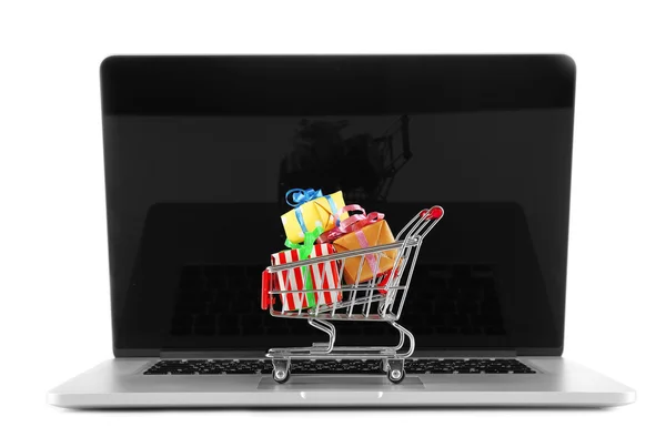 Laptop com carrinho de compras pequeno cheio de presentes isolados no fundo branco — Fotografia de Stock