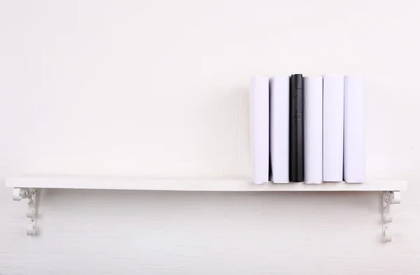 Libros en blanco con uno negro en la estantería sobre fondo de pared blanco —  Fotos de Stock