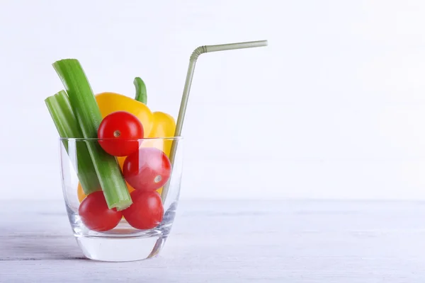 Vegetables in glass with tube on color wooden planks background — Stock Photo, Image