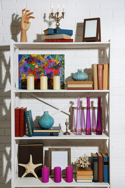Bookshelves with books and decorative objects on brick wall background