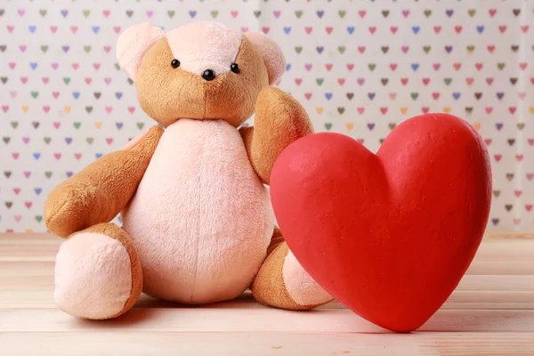 Teddy beer met rood hart op feestelijke achtergrond — Stockfoto