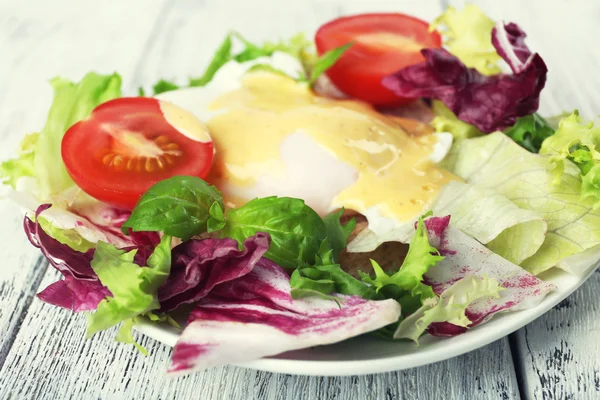 Toast with egg Benedict and tomato on plate on wooden table — Stock Photo, Image