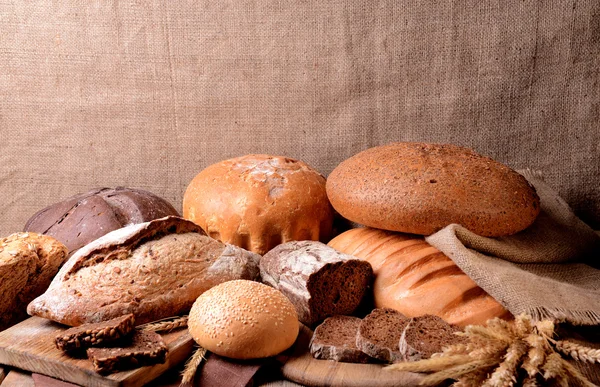 Різний хліб на столі на мішкуватому фоні — стокове фото
