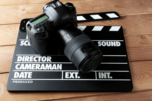 Photo camera and movie clapper on wooden background — Stock Photo, Image