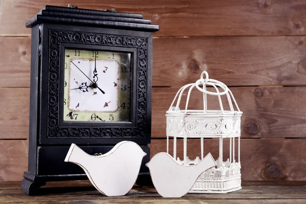 木製の背景にテーブルの上の装飾的な鳥とレトロな時計 — ストック写真