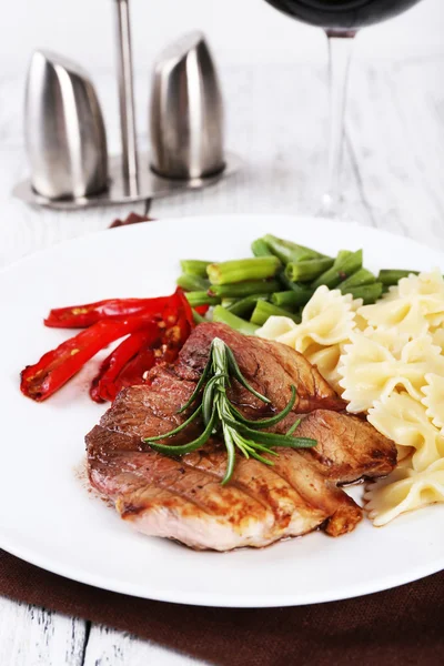 Steak with vegetables and pasta on plate on wooden plate — Stock Photo, Image