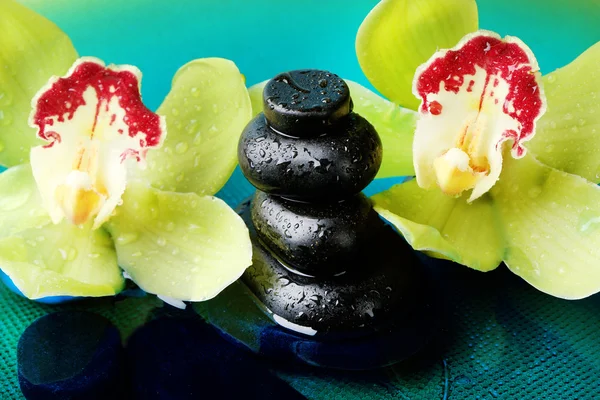 Piedras de spa con gotas de agua y hermosa orquídea en flor en primer plano de agua —  Fotos de Stock