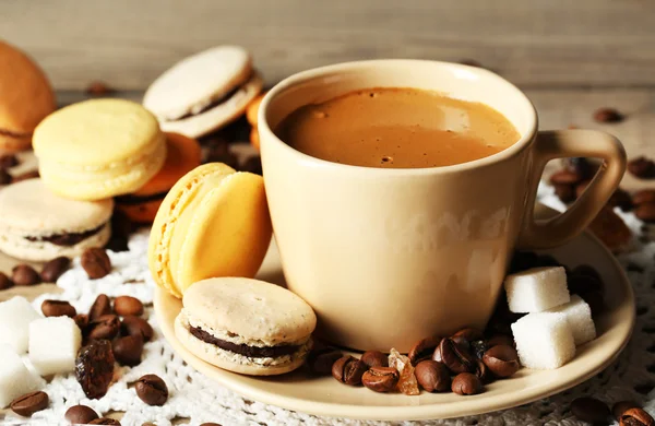 Macarons colorés doux et café en tasse sur fond de table en bois — Photo