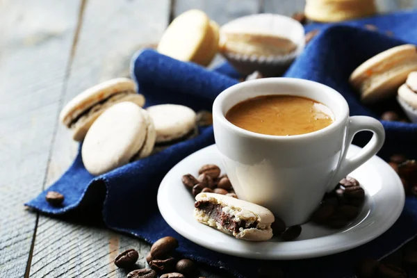 Zachte kleurrijke bitterkoekjes en koffie in een mok op houten tafel achtergrond — Stockfoto