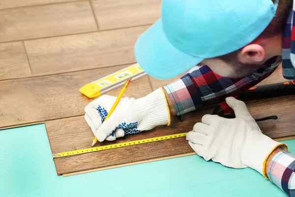 Trabalhador de carpinteiro instalando piso laminado na sala — Fotografia de Stock