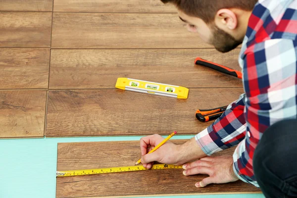 Carpenter pracovník instalace laminátové podlahy v místnosti — Stock fotografie