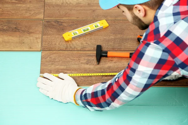 Trabalhador de carpinteiro instalando piso laminado na sala — Fotografia de Stock