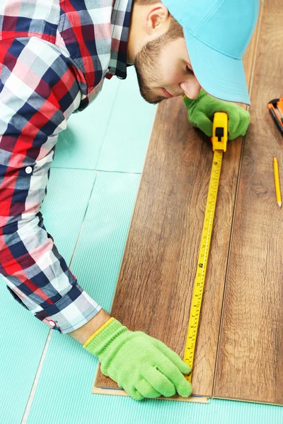 Trabalhador de carpinteiro instalando piso laminado na sala — Fotografia de Stock