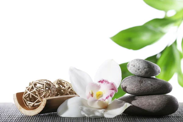 Still life of spa stones on bamboo mat surface with green leaves isolated on white — Stock Photo, Image